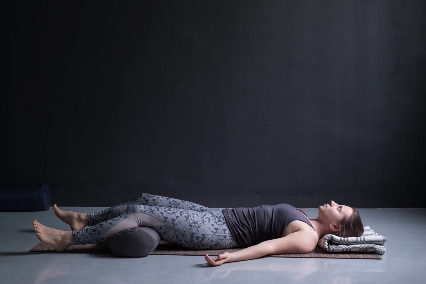 Femme pratiquant une pose de yoga avec un bolster pour le soutien