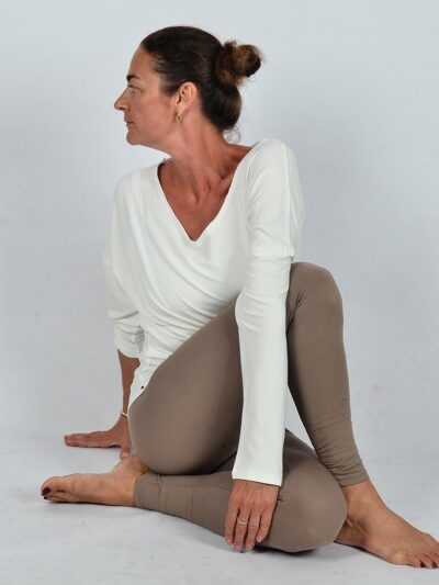 Femme habillée d'un pantalon beige moulant et un top à manches longues bleu marine avec un joli décolleté dans le dos