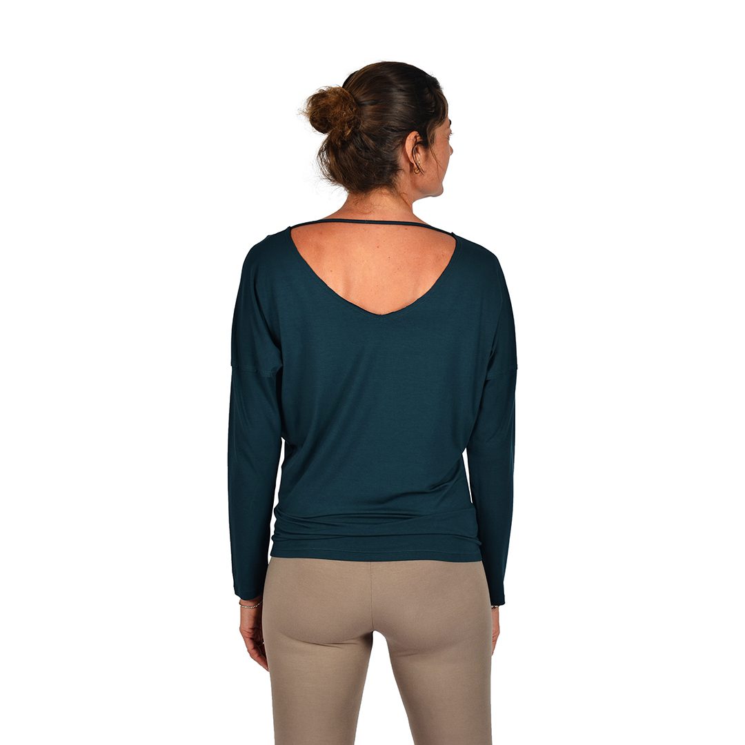 Femme habillée d'un pantalon beige moulant et un top à manches longues bleu marine avec un joli décolleté dans le dos