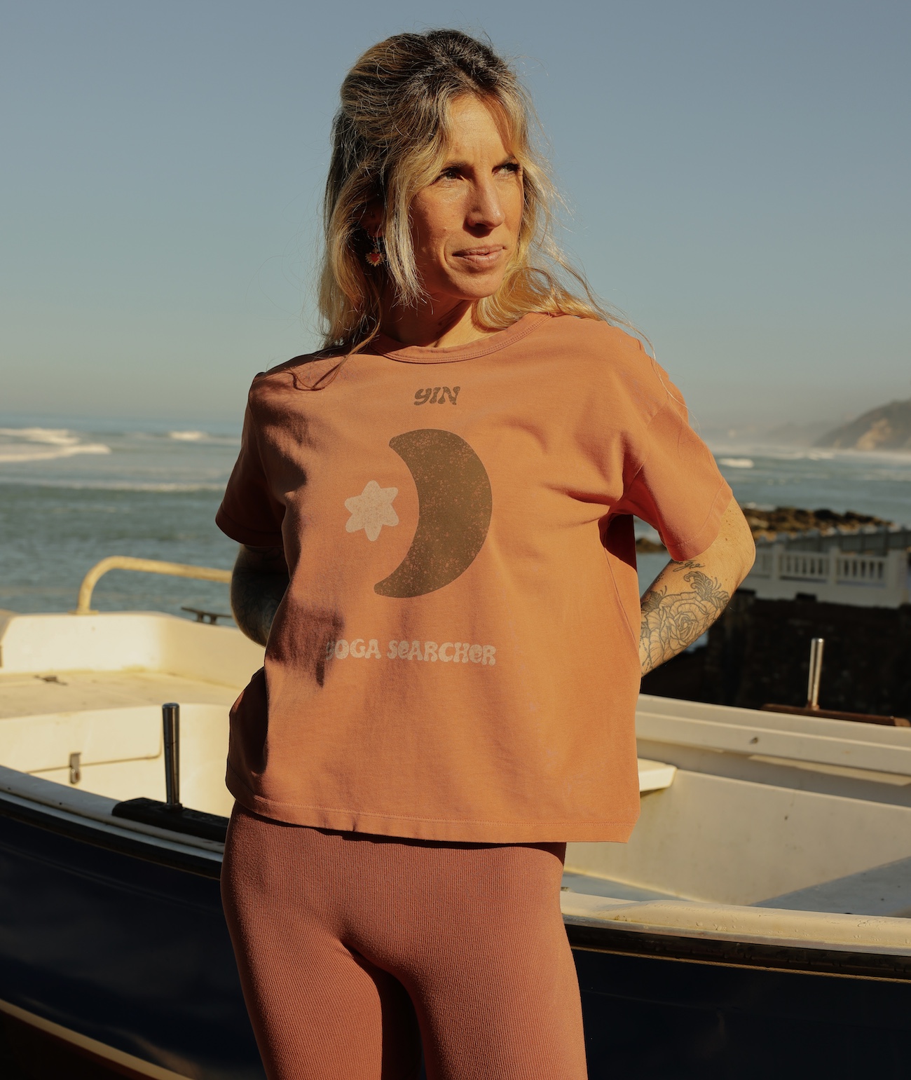 Femme en tenue de yoga orange près de la mer