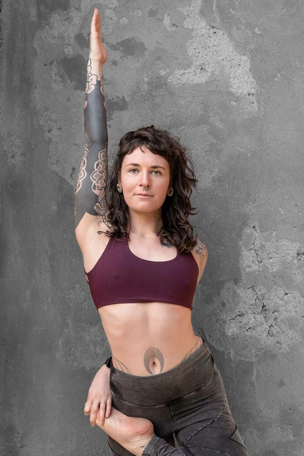 Personne faisant une pose de yoga contre un mur gris