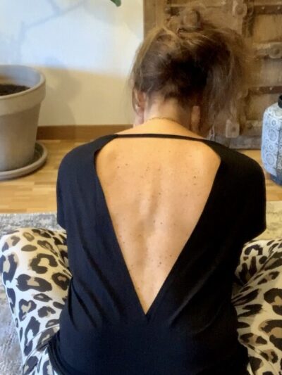 Yogini en yoga aérien avec un top de yoga ouvert dans le dos de coloris noir