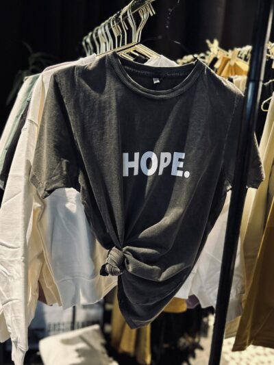 T-shirt gris foncé stone washed à col rond et coupe droite, suspendu sur cintre, avec inscription blanche Hope ou Espoir