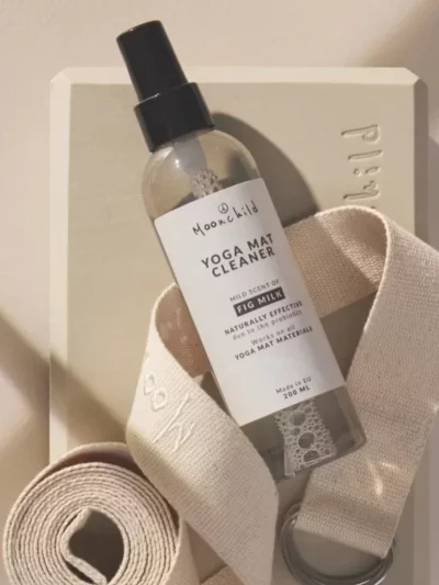 Spray transparent nettotant tapis de yoga Moonchild au lait de figue posé sur un bloc de yoga et une sangle de yoga
