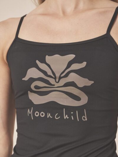 Femme portant un débardeur de sport noir à fines bretelles avec un dessin de fleur de lune et marque moonchild à l'avant