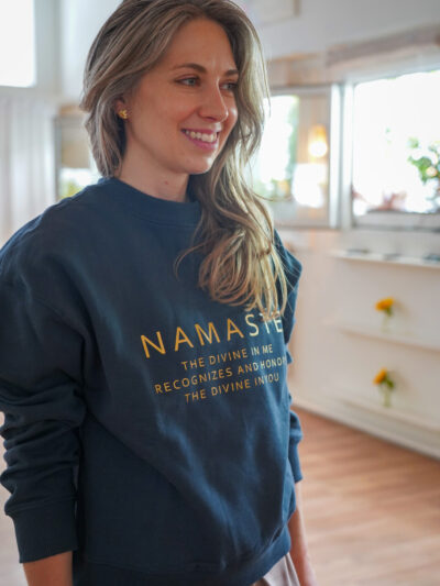 Jeune femme portant un sweatshirt bleu marine avec inscription namaste et définition en lettres dorées