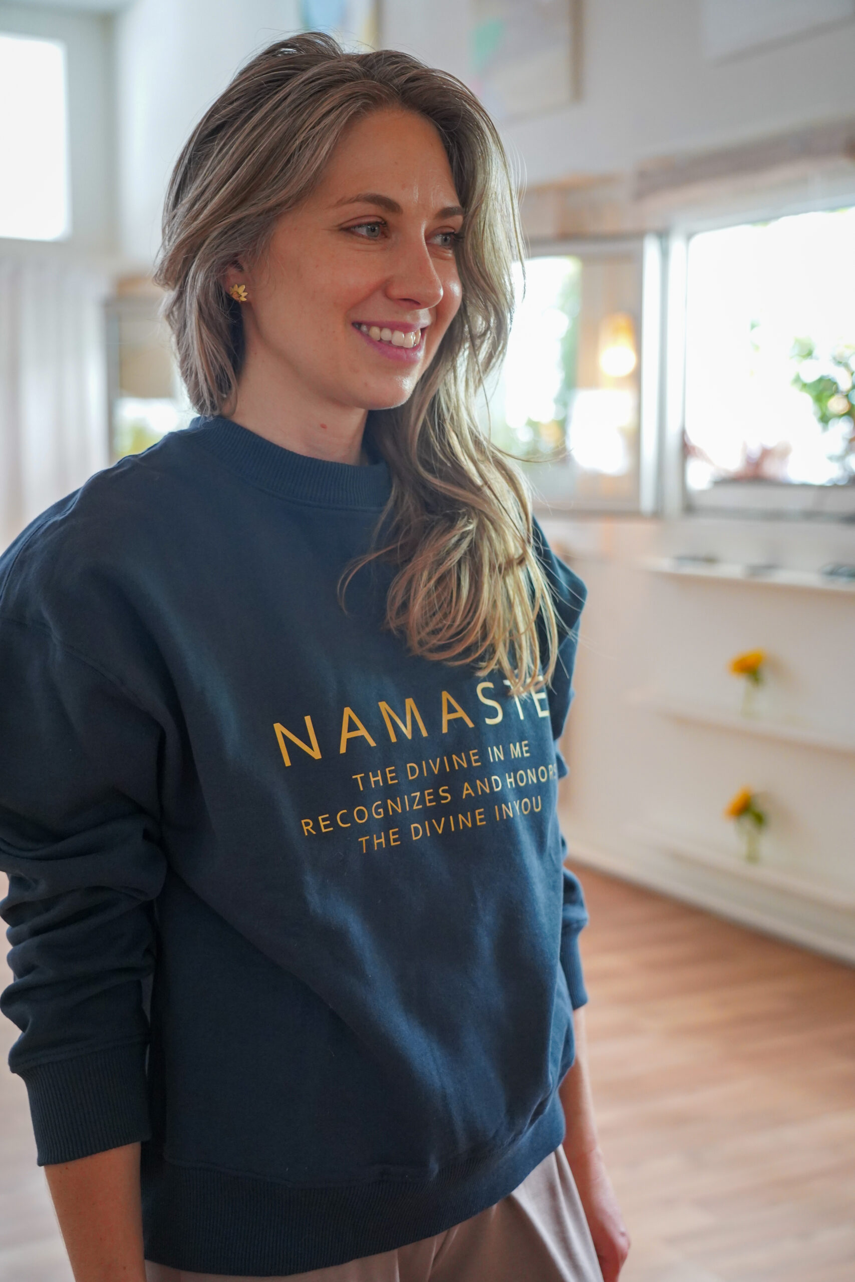Jeune femme portant un sweatshirt bleu marine avec inscription namaste et définition en lettres dorées
