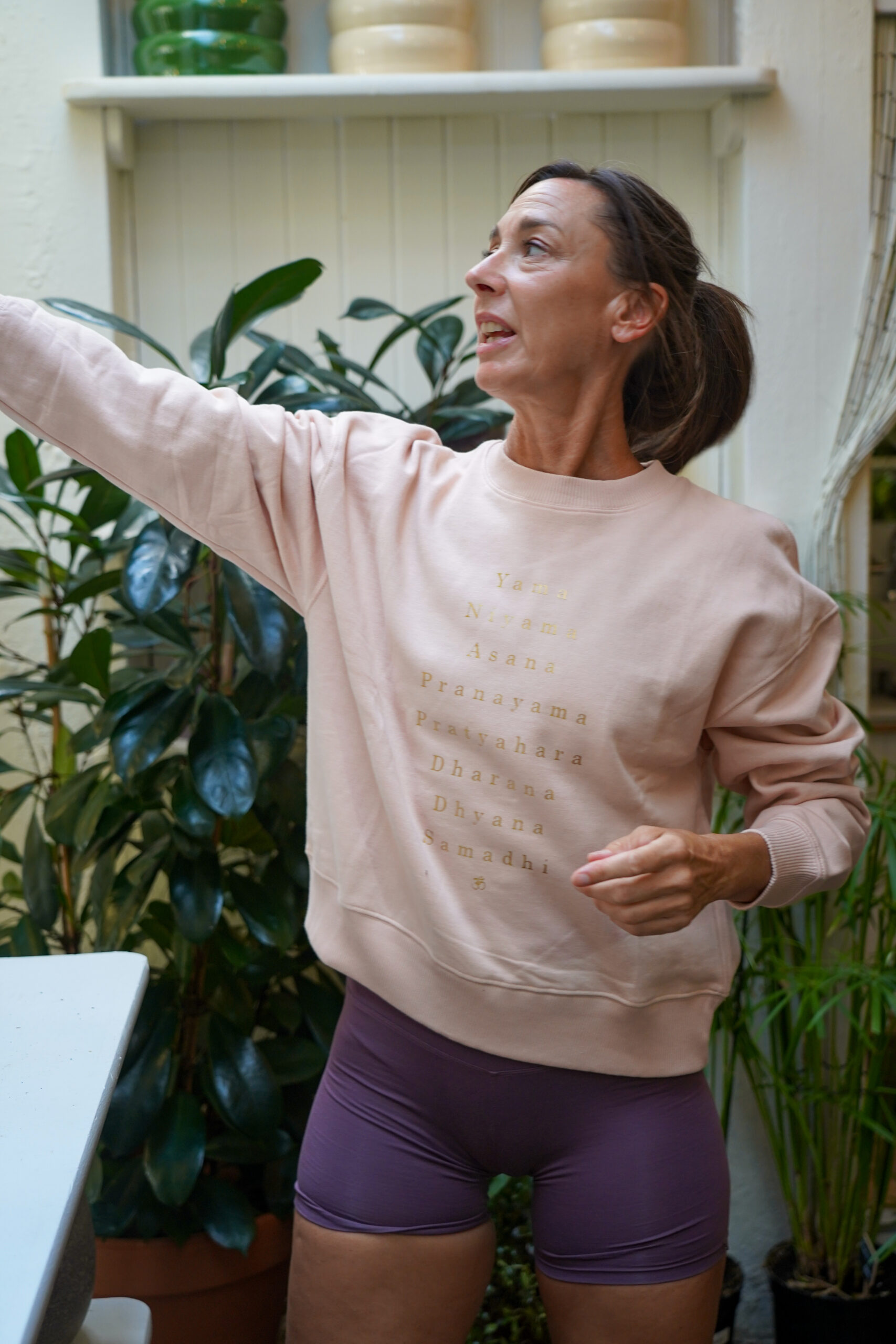 Femme faisant des étirements dans un espace intérieur vert.
