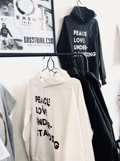 2 Sweatshirts suspendus sur contre avec inscription peace, love, understanding, de coloris blanc et noir