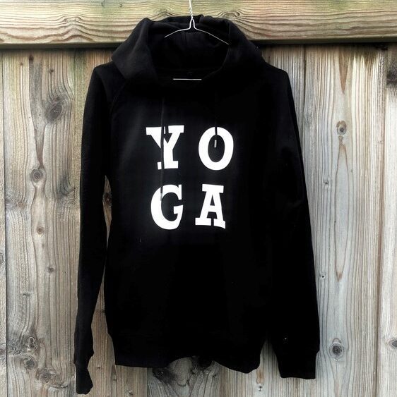 Sweatshirt à capuche noir avec inscription en grosses lettres blanches yoga, suspendu sur cintre