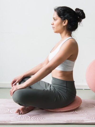 Femme méditant en position assise sur coussin rose