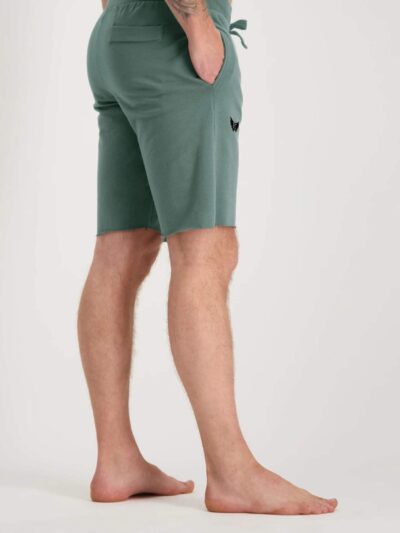 Jambes d'homme portant un short de sport vert foncé avec logo Renegade Guru