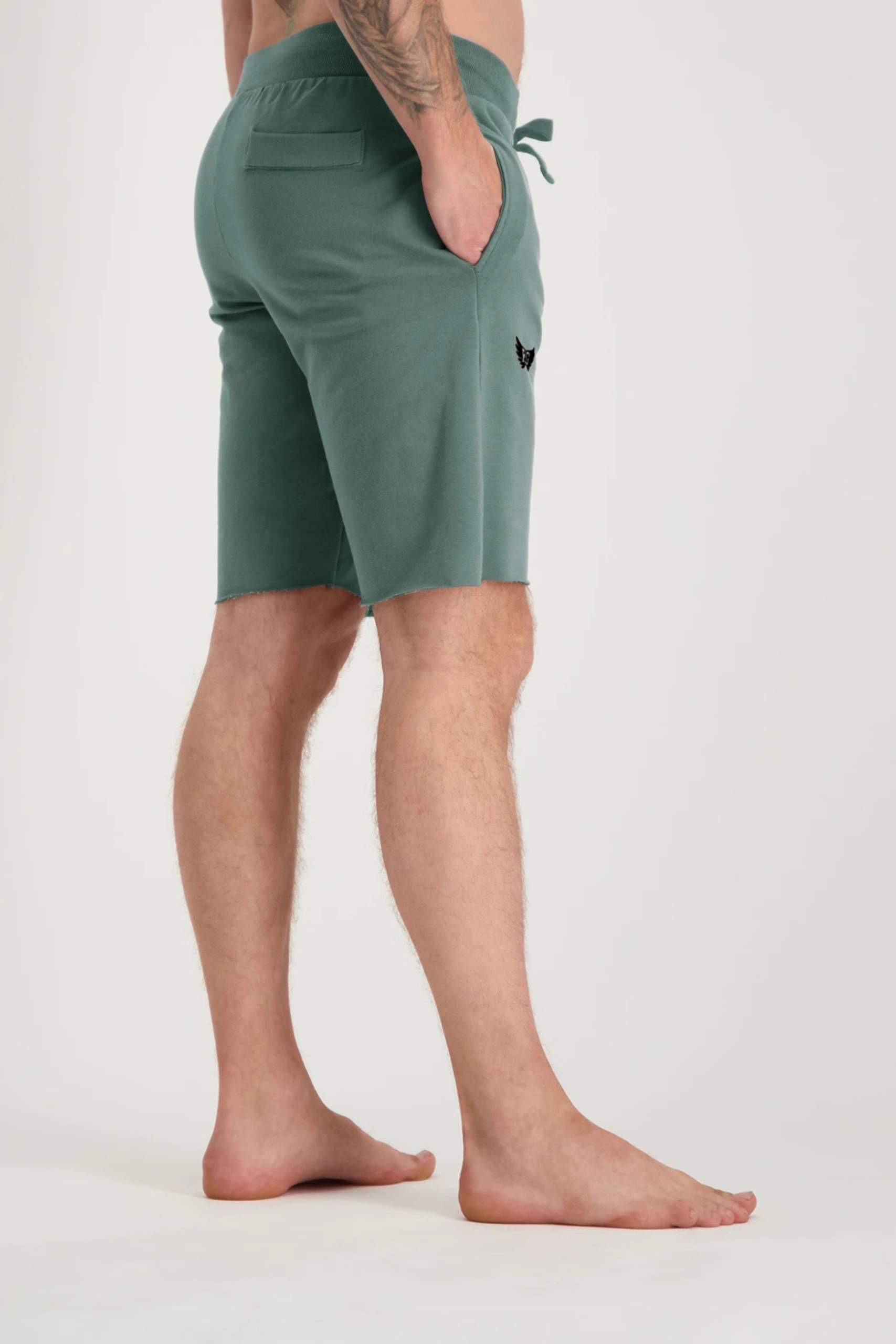 Jambes d'homme portant un short de sport vert foncé avec logo Renegade Guru