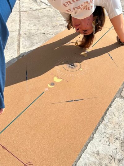 Femme en chien tête en bas sur tapis de yoga en liege avec motifs centrés colorés par Yogom marque française