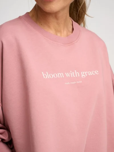 Femme portant un sweat rose à manches ¾ bouffantes et message imprimé devant