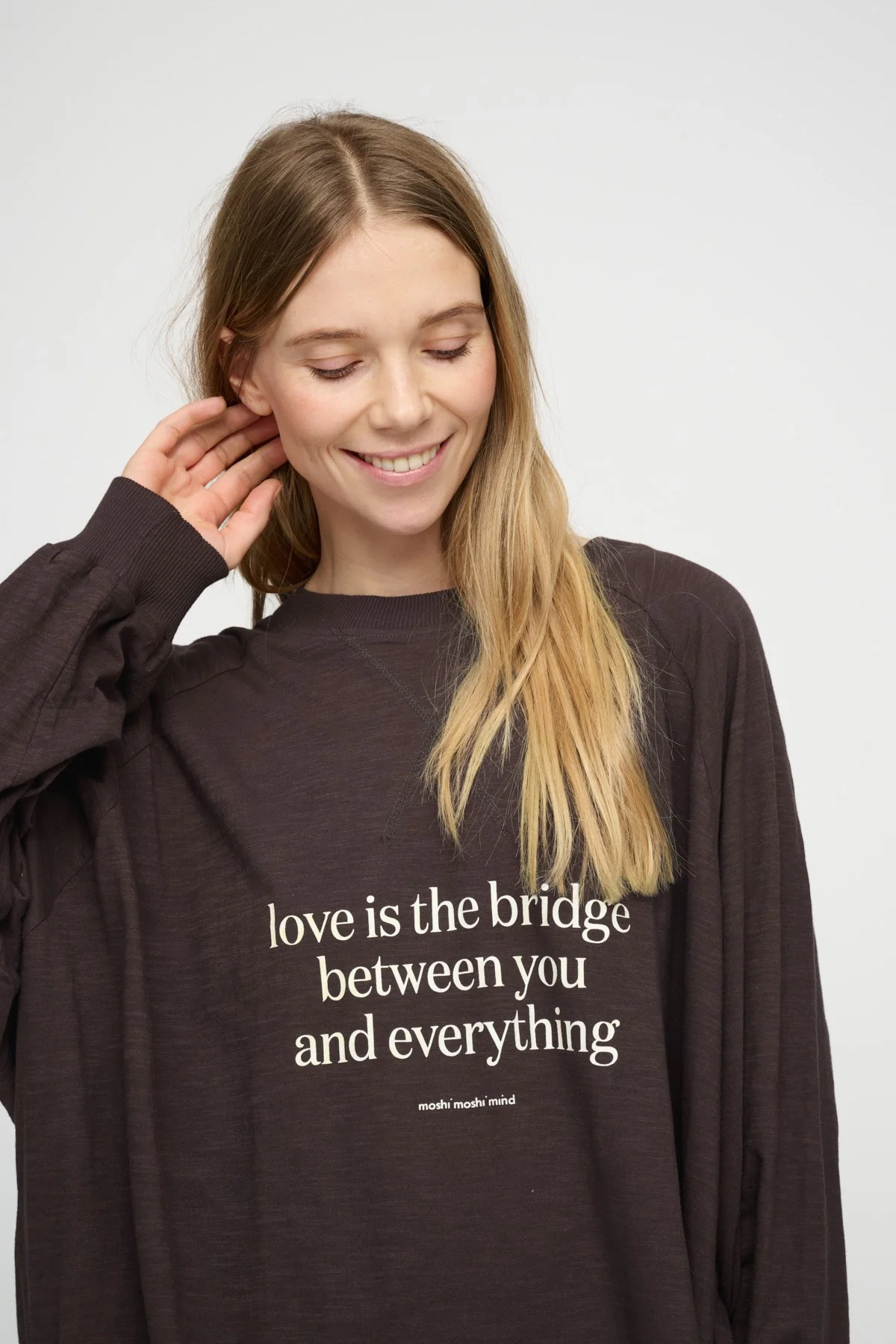 Femme souriante portant un sweat brun à message