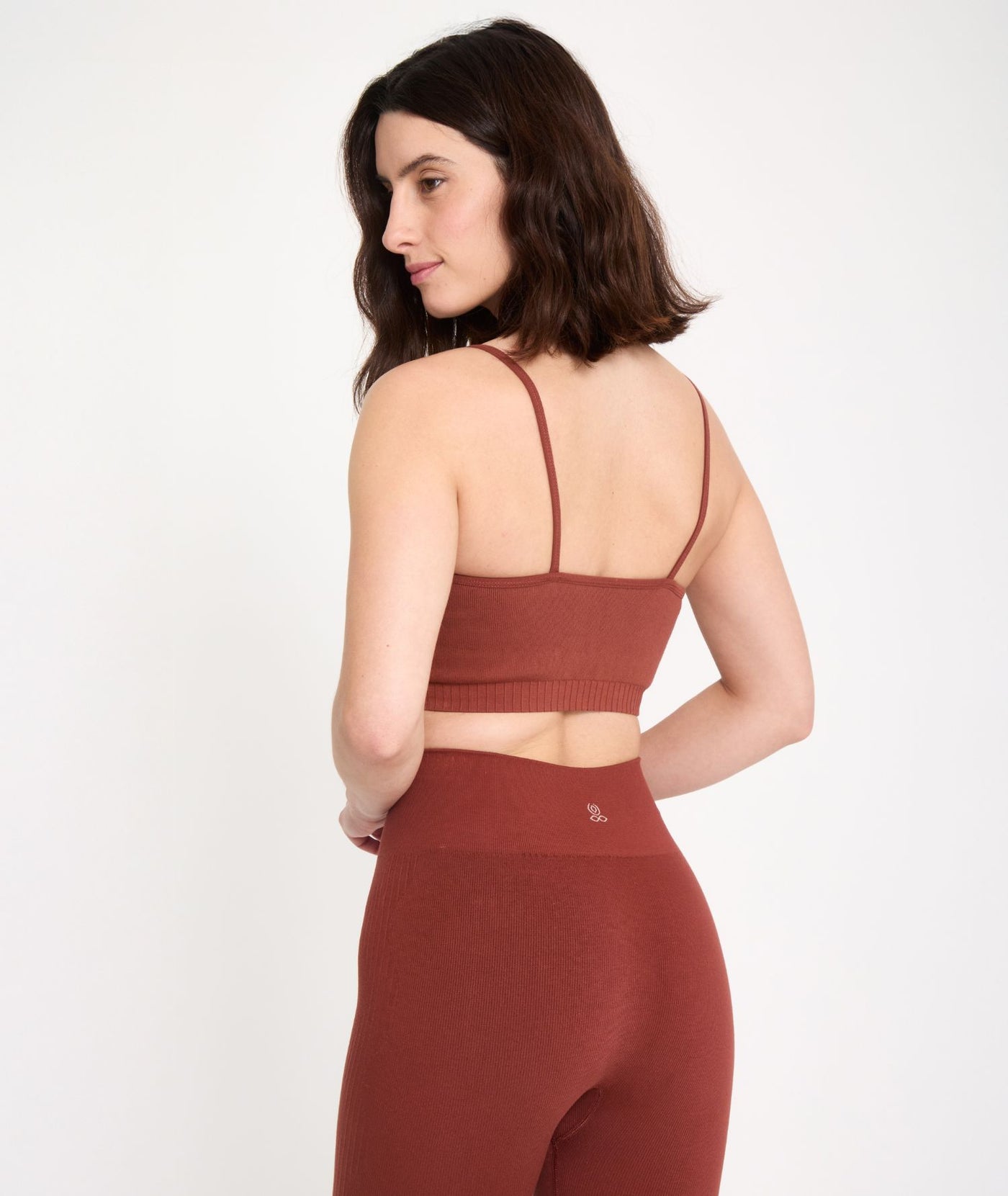 Jeune femme vue de dos qui porte une brassière et un legging de sport de coloris orange