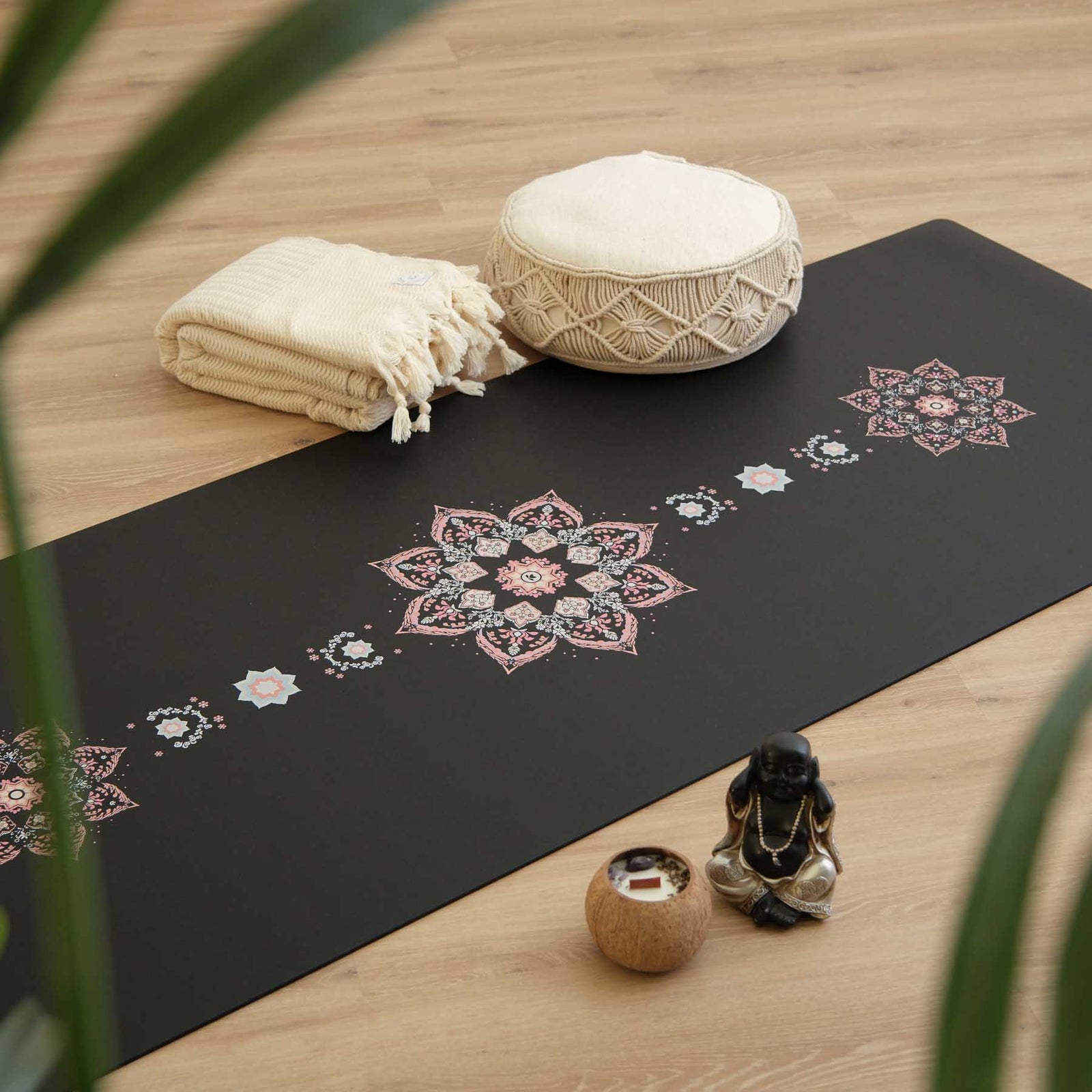 Tapis de yoga noir avec des motifs de mosaïque florale inspirée d'Orient, dans une ambiance de pratqiue de yoga avec des coussins de méditation et des bougies
