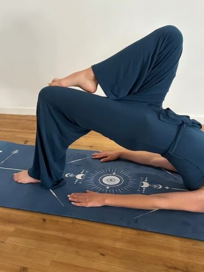 Femme qui fait un pont sur un pied en pilates sur un tapis bleu avec motifs