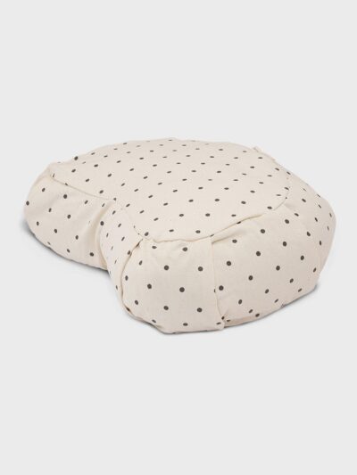 Coussin de méditation et de yoga de forme demie-lune et de coloris écru avec petits pois noirs vu de côté
